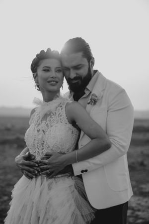 A black and white portrait of a couple in wedding attire sharing an intimate embrace.