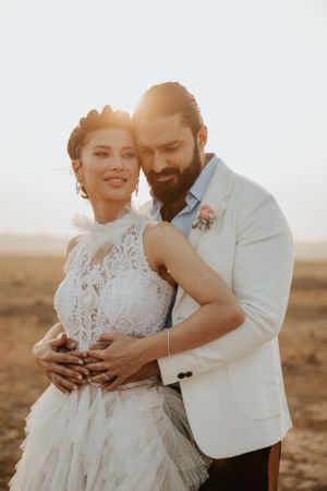 A tender moment between newlyweds in formal attire captured during golden hour.