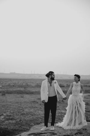 A couple shares a quiet moment in wedding attire against a misty desert backdrop.