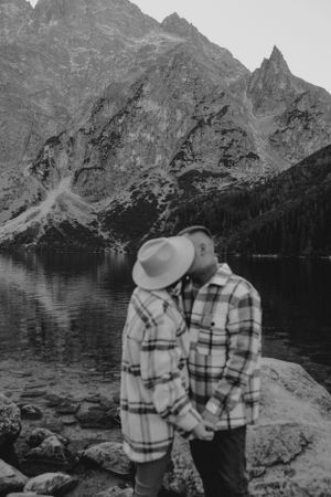 Black and white photo of a romantic moment by a mountain lake with dramatic peaks.