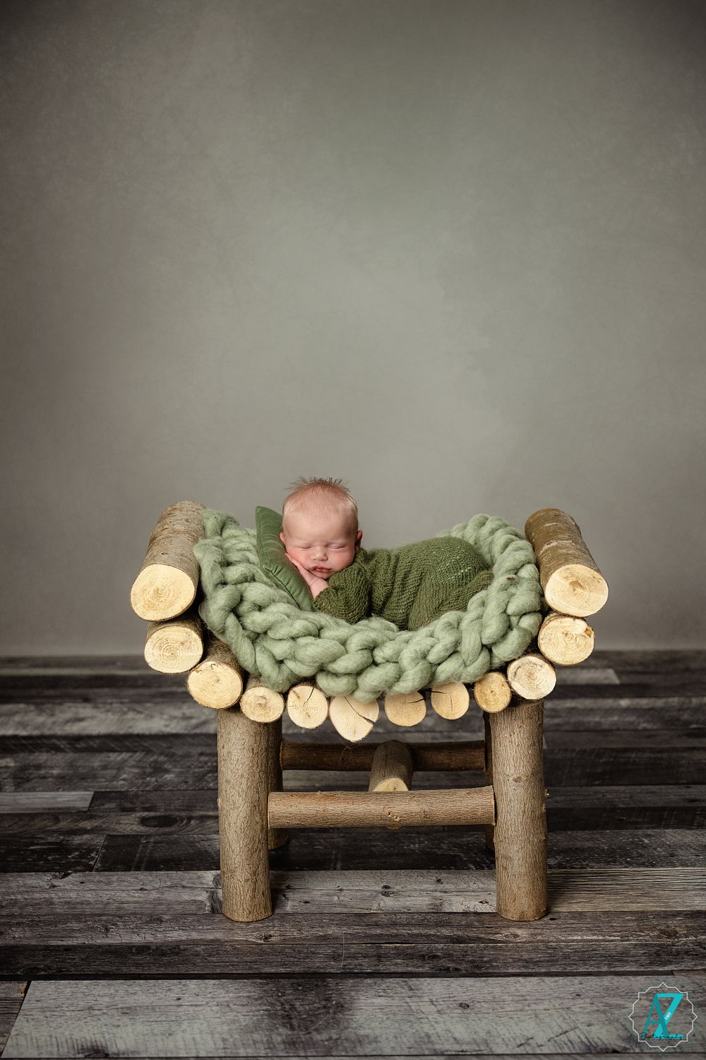 Rustic wooden bench decorated with log slices and green knit bedding for newborn photography.