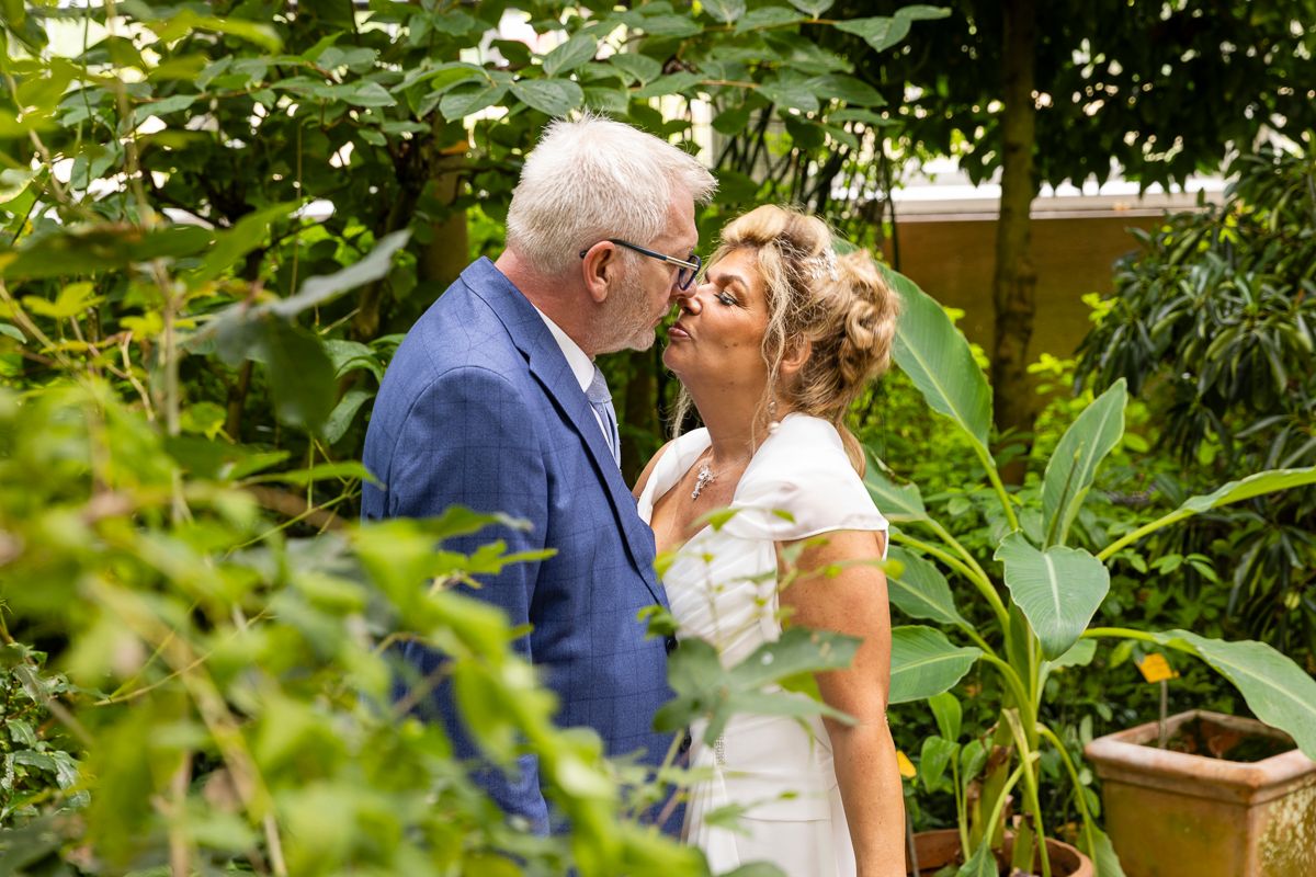 A romantic moment captured between newlyweds in a green garden setting.