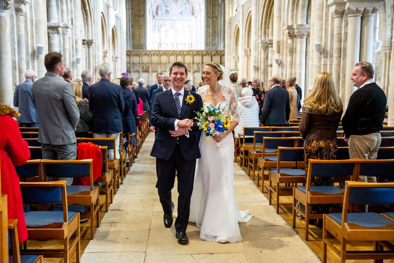 Wide view of cathedral wedding ceremony with guests seated in wooden pews.