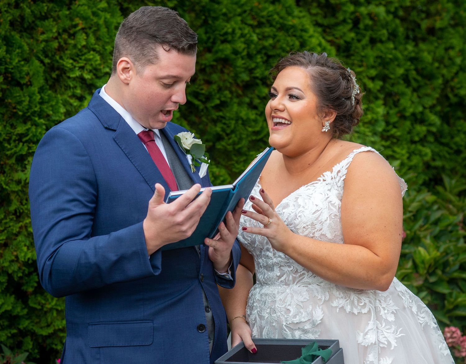 Couple laughs together while reading from a small book during their wedding ceremony.