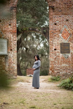 Maternity portrait framed by brick archway in historic setting in Beaufort, South Carolina at the Sheldon Church Ruins.