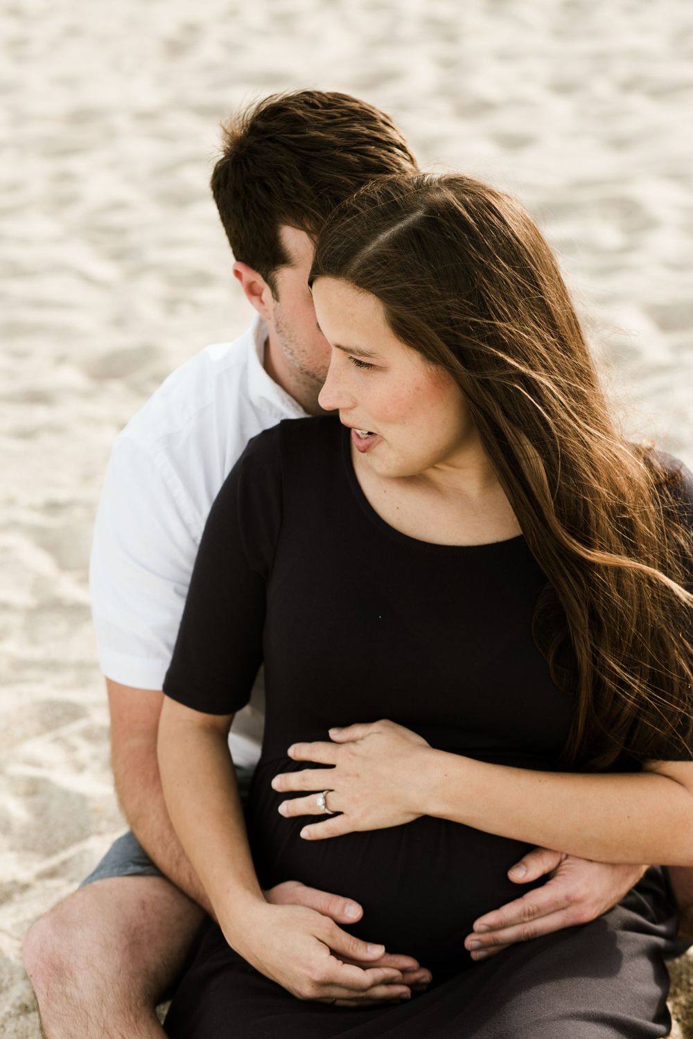 Expectant couple shares intimate moment on sandy beach during maternity photoshoot on Mitchelville Beach in Hilton Head, SC.