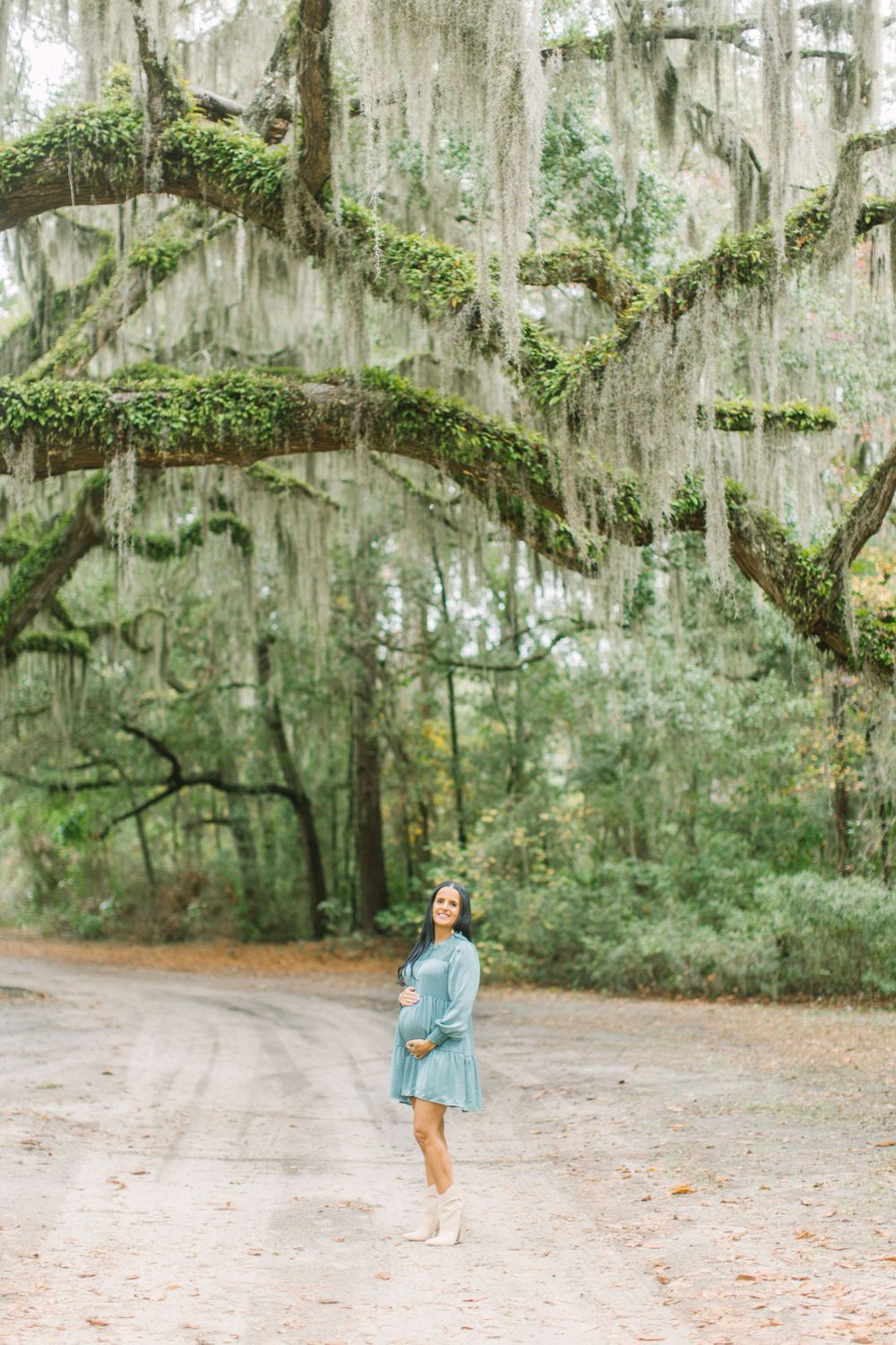 Spanish moss draped over trees frames dirt path in moody Southern landscape on Saint Helena in South Carolina near chapel ruins.
