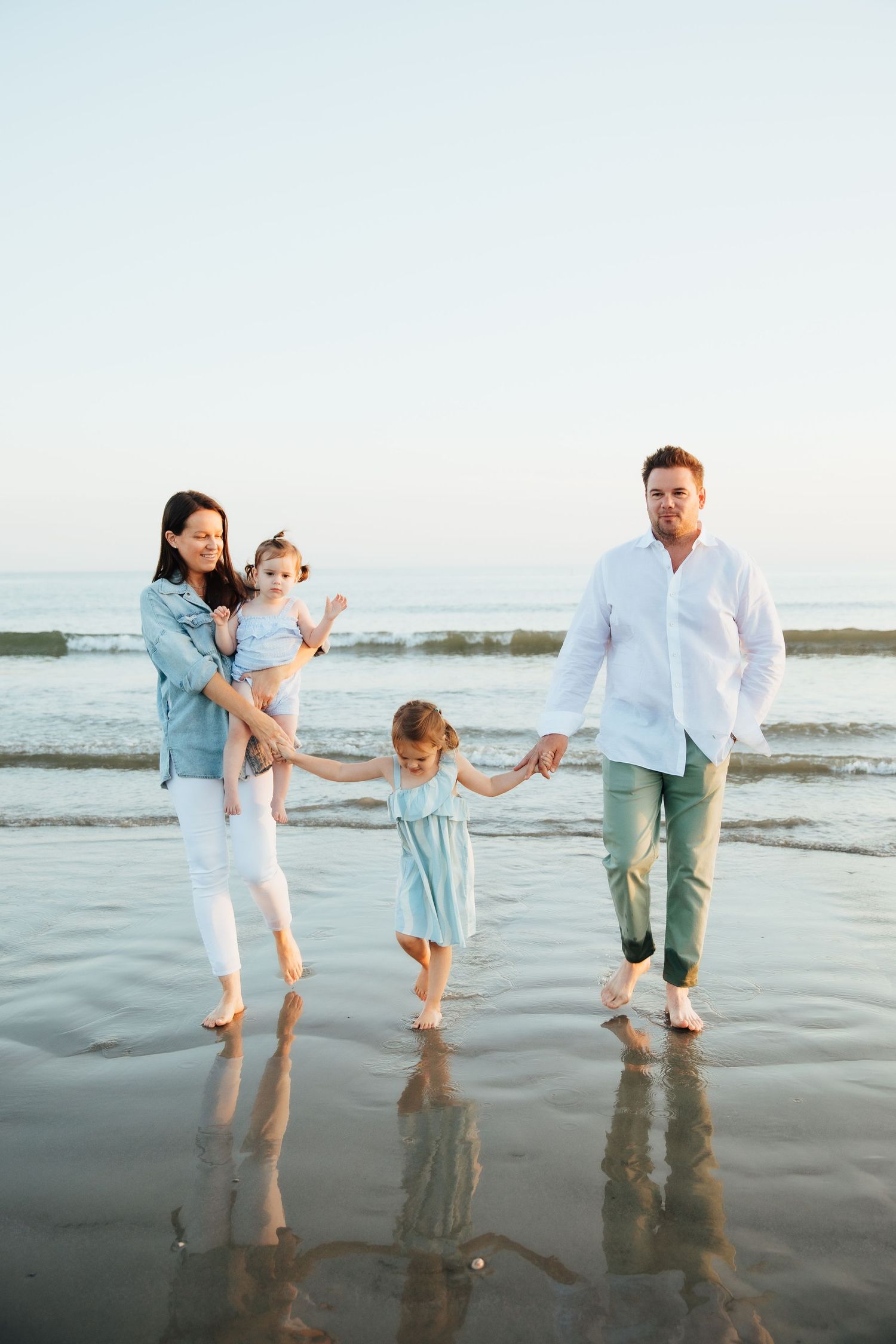 Family walking barefoot together along wet sand at the beach during sunset. second beach Middletown rhode island