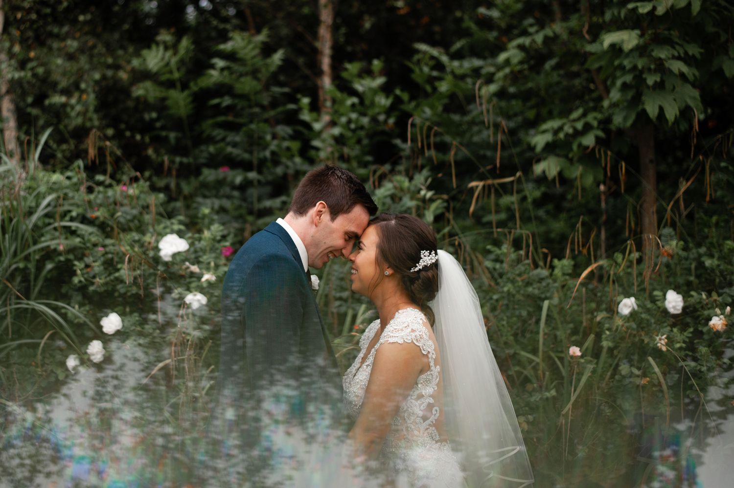 Newlyweds share an intimate moment in a garden filled with white flowers.