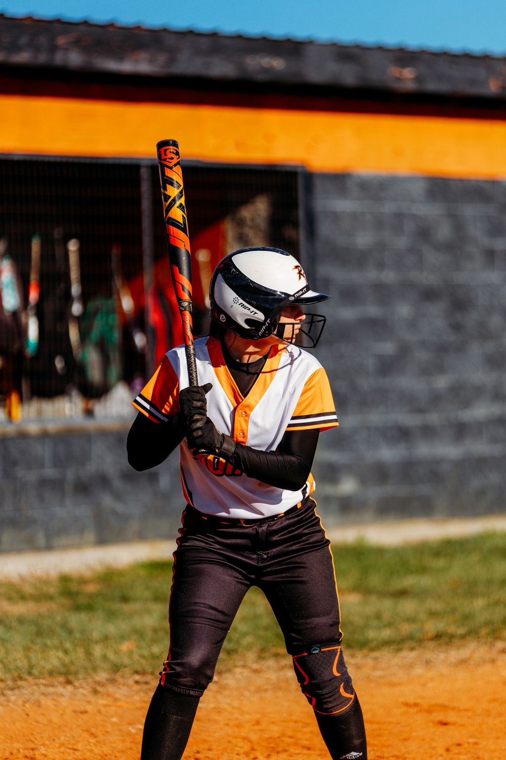 Female softball batter in Indians uniform ready at plate holding bat in batting stance.