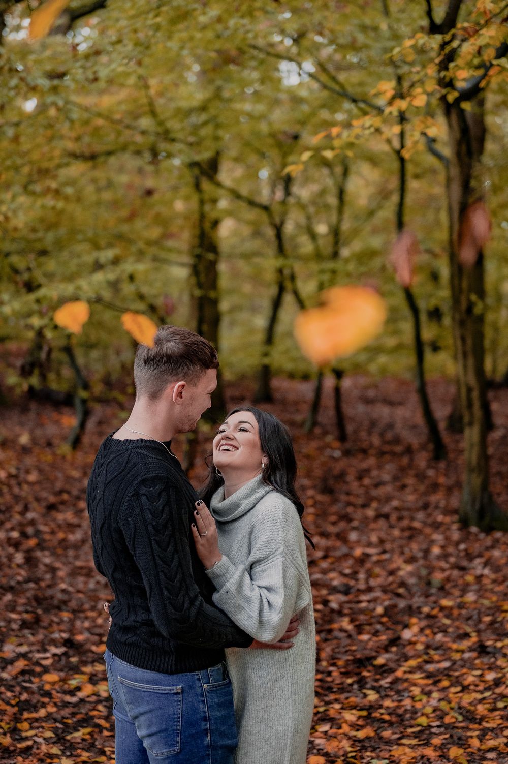 A joyful moment captured between a couple surrounded by autumn foliage and falling leaves.
