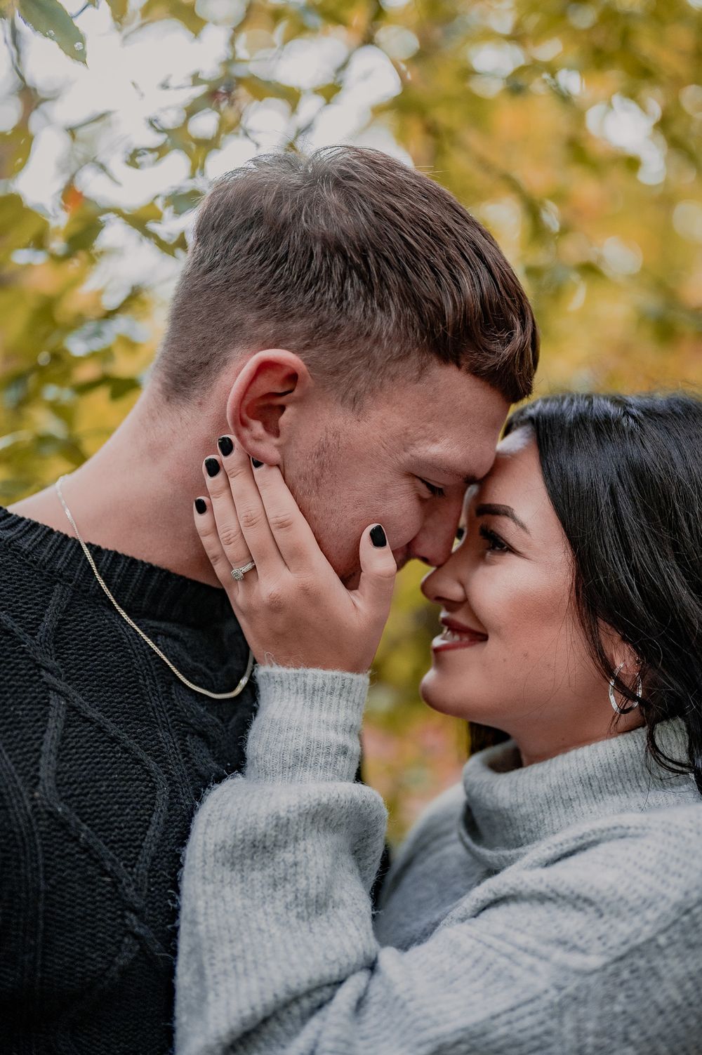 Intimate autumn engagement photo with couple in matching gray sweaters.