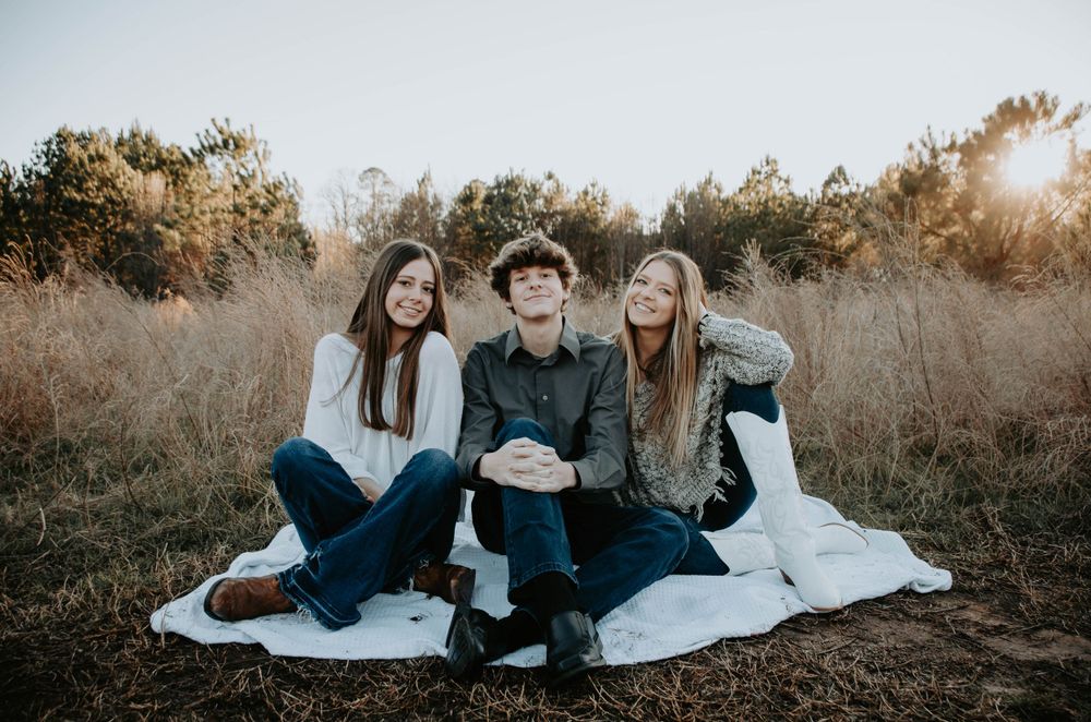 Smiling family posed together outdoors, capturing a warm and candid moment during a portrait session