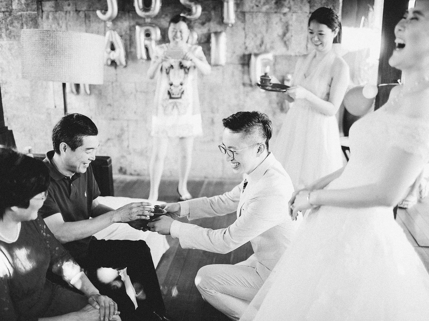 A bride and groom with friends at a table during a Chinese tea ceremony in Bulgari Resort Bali.