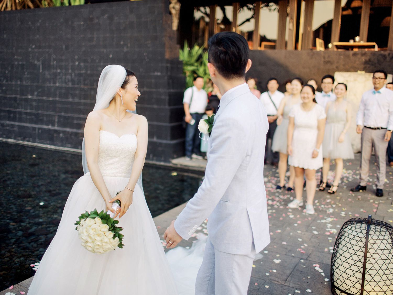 A bride and groom standing near a pool at a wedding in Bulgari Resort Bali.