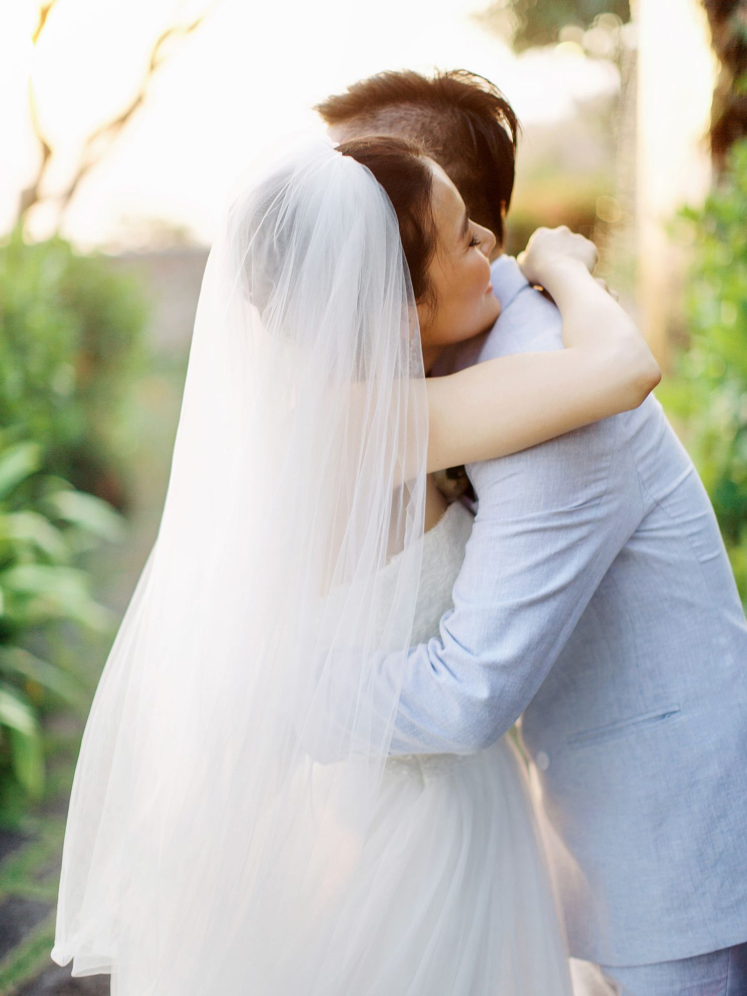 Bride and groom embracing with scenic backdrop of Bulgari Resort Bali.