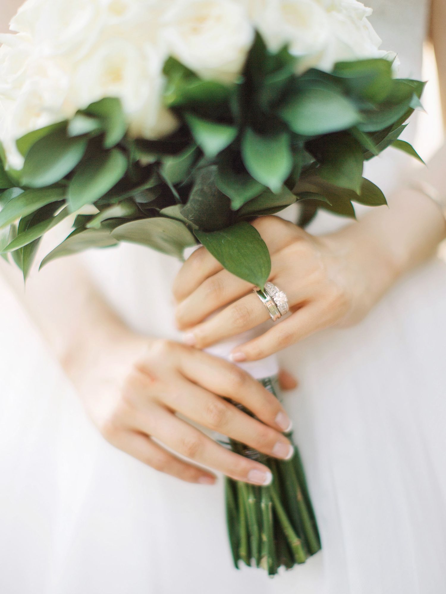 A woman gracefully holds a bouquet of white roses, adding elegance to the luxurious ambiance of Bulgari Resort Bali.