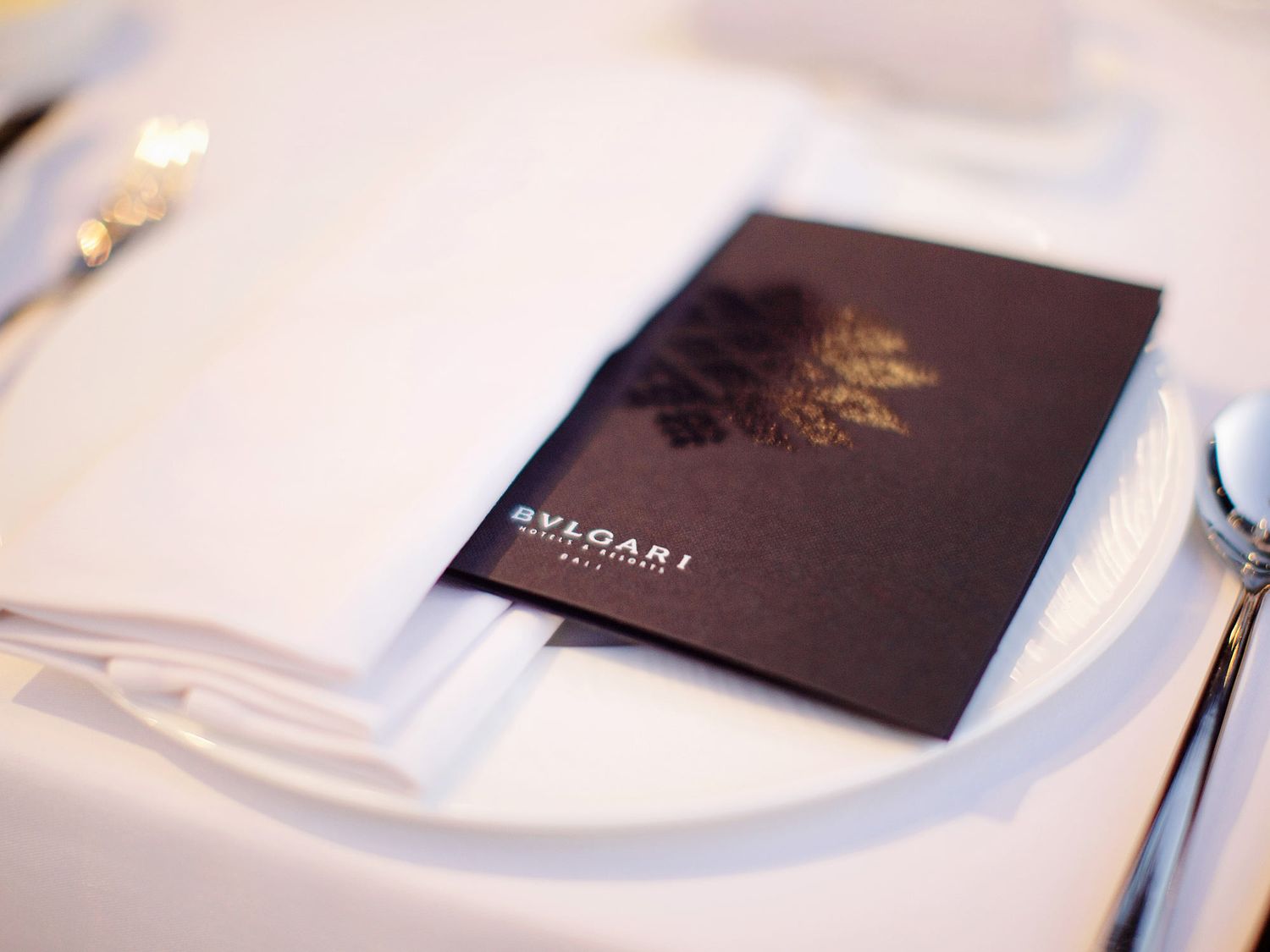 A luxurious wedding reception at Bulgari Resort Bali featuring a plate with silverware and a napkin.