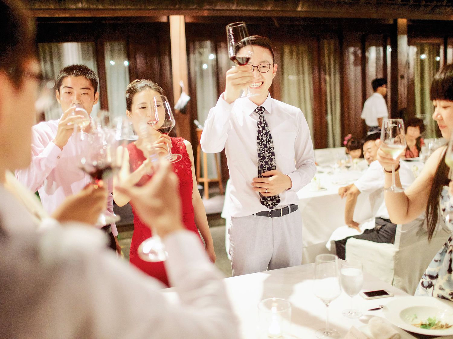 A luxurious wedding reception at Bulgari Resort Bali, featuring a group of people gathered around a table with wine glas