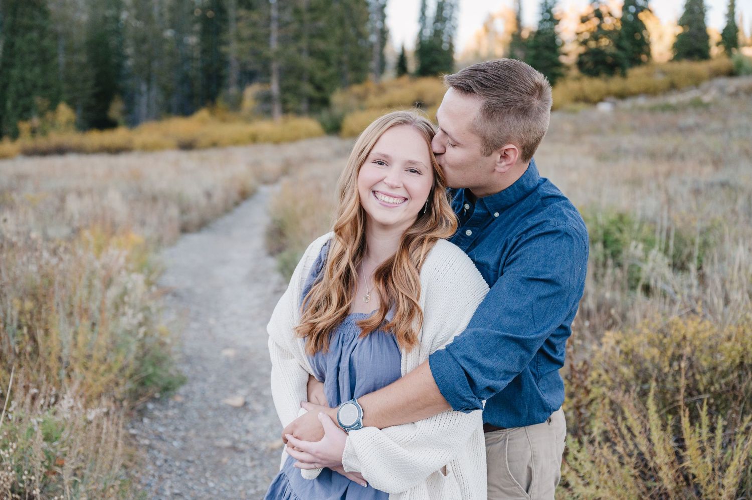 Happy couple sharing a laugh during their mountain engagement photo session.