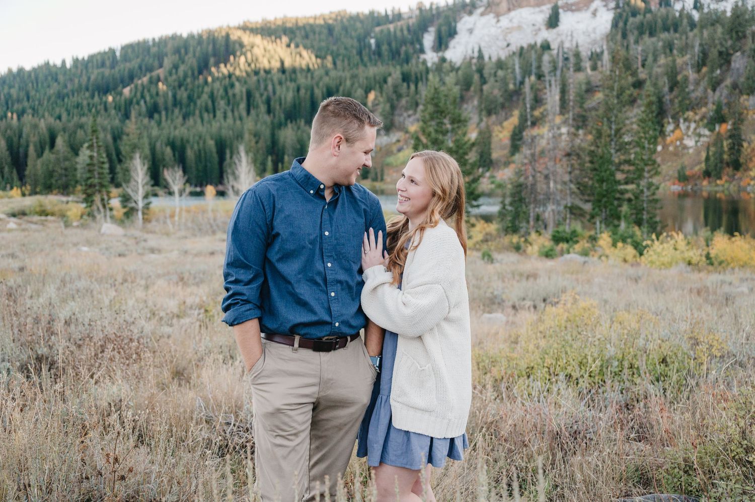 Couple embracing in a scenic mountain meadow on a fall afternoon.