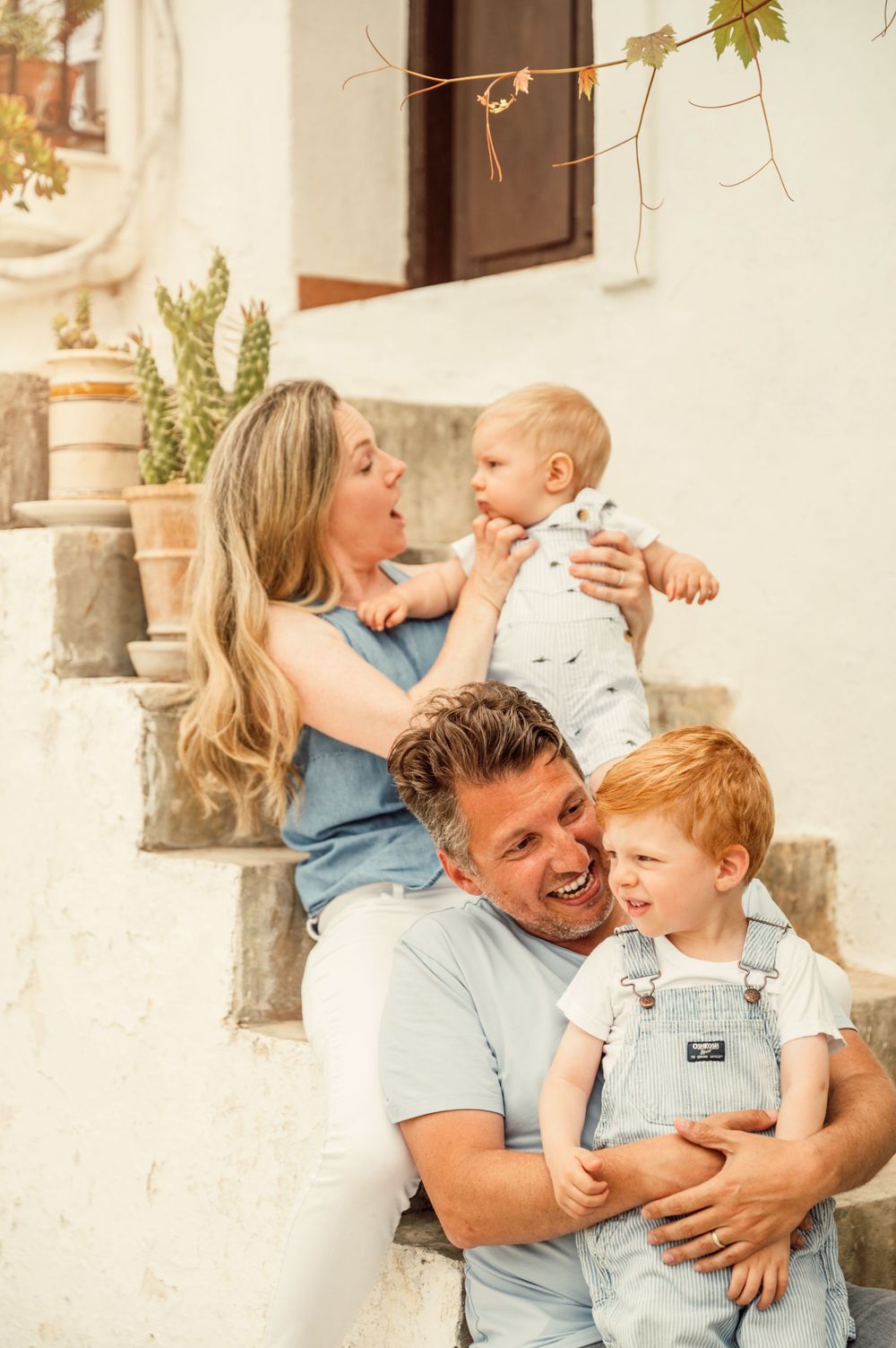 Candid family moment sharing laughs while sitting on outdoor stone steps.