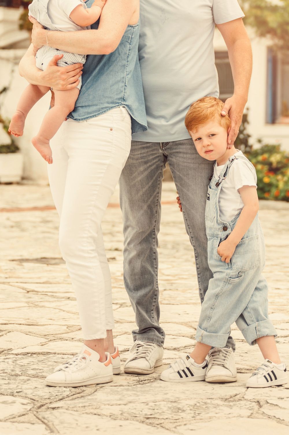 Family standing together on stone pavement wearing casual clothes and sneakers.