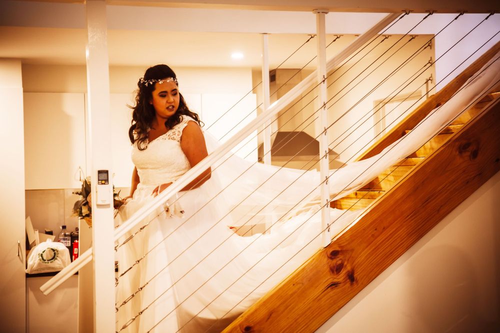 Natural light streams through windows onto wooden staircase during wedding celebration.