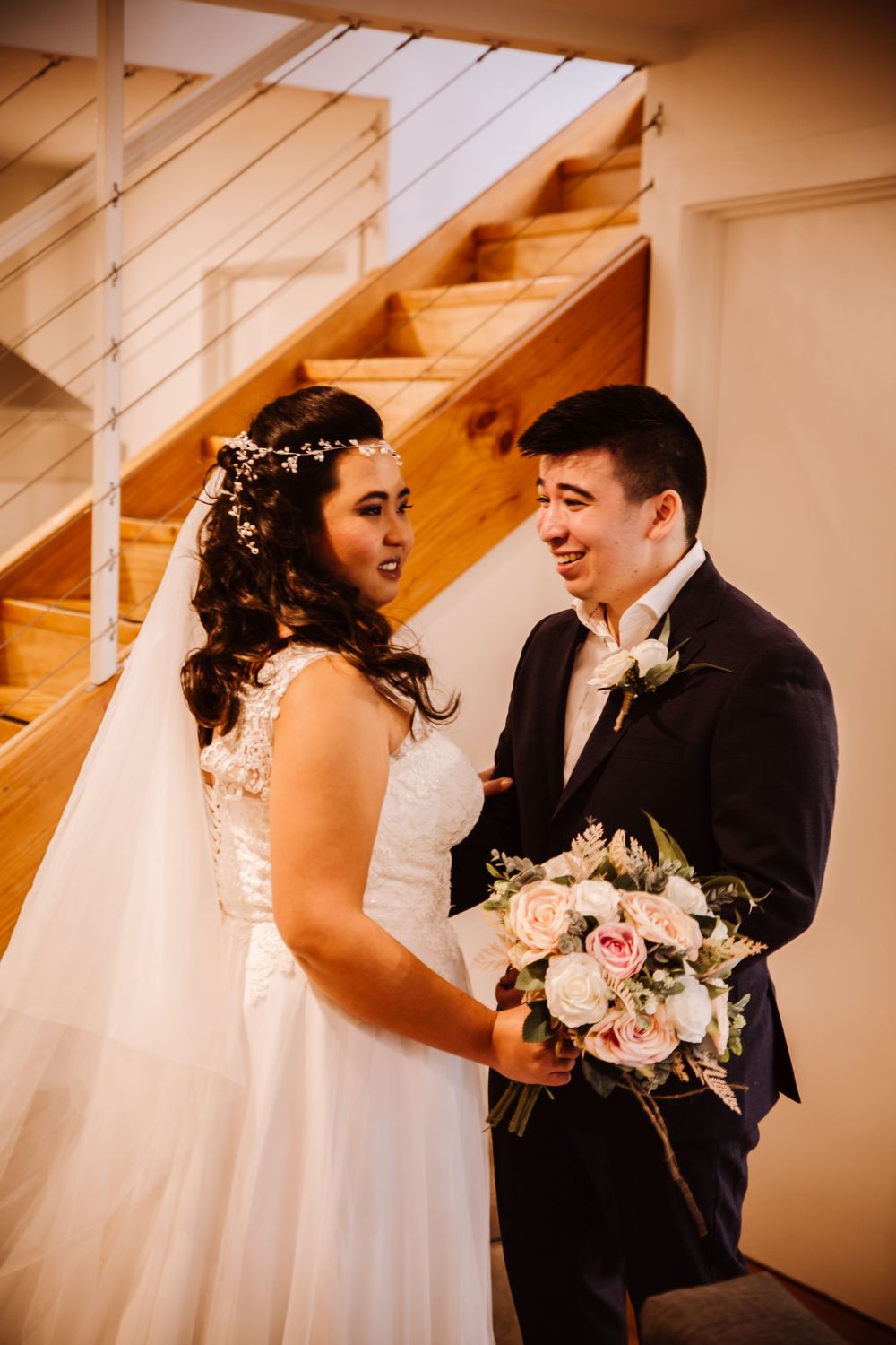 Wedding couple dancing and twirling under wooden beams in warm lighting.