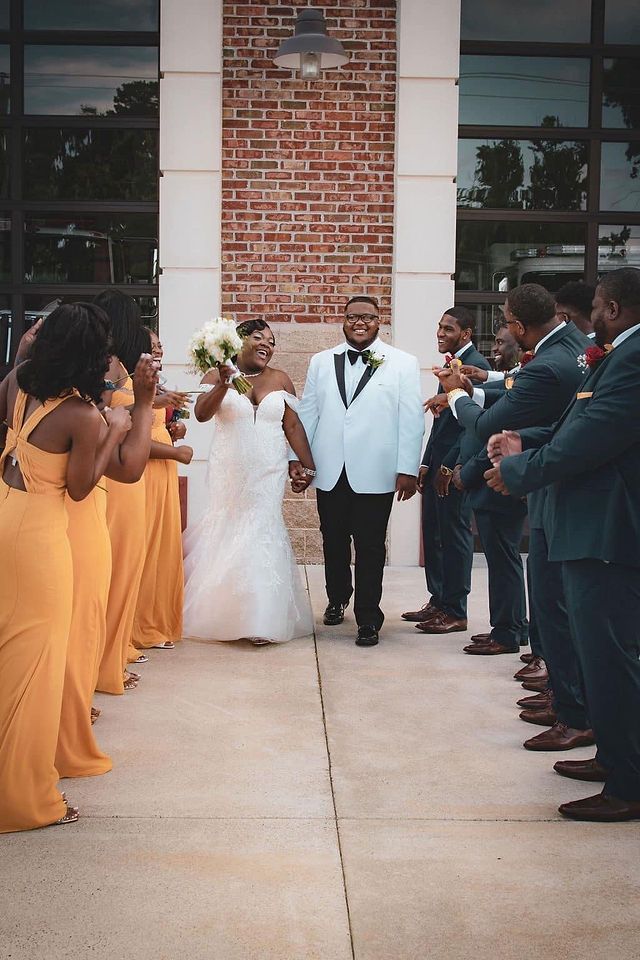 Wedding party lined up in orange and navy attire during outdoor ceremony exit.
