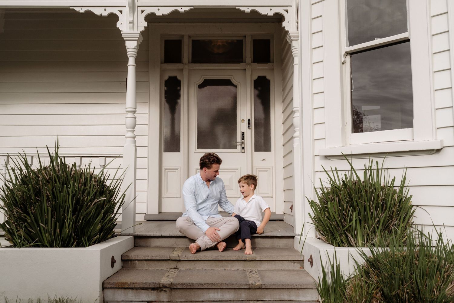A photograph of a father and son at hone on their doorstep.  Natural Family photo
