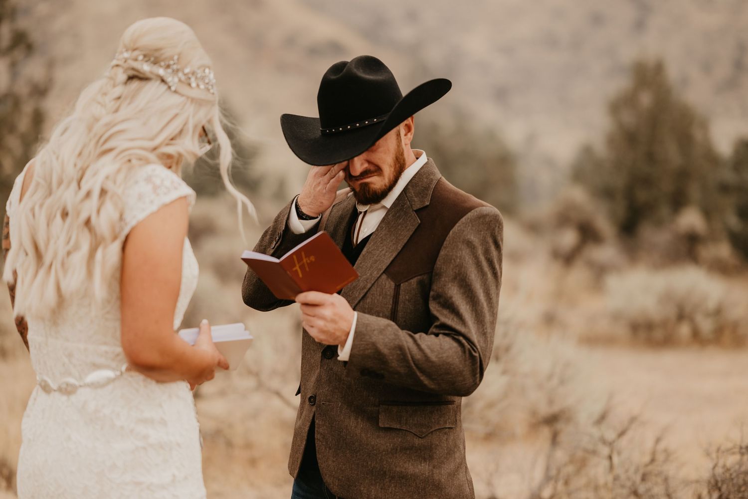 Wedding couple in rustic western attire sharing emotional moment during ceremony.