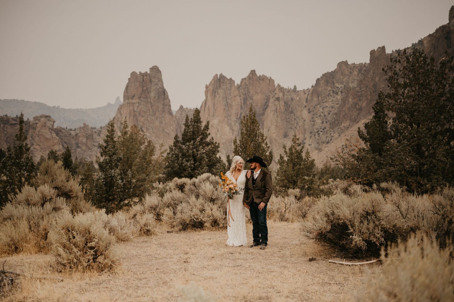 A couple stands together against dramatic desert rock formations in Smith Rock State Park.