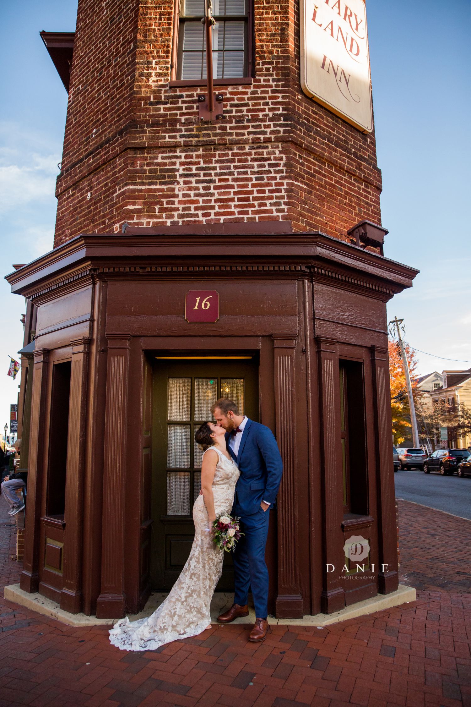 Bride in a lace dress and groom in Navy suit kiss during thier first look in front of Maryland Inn in Annapolis