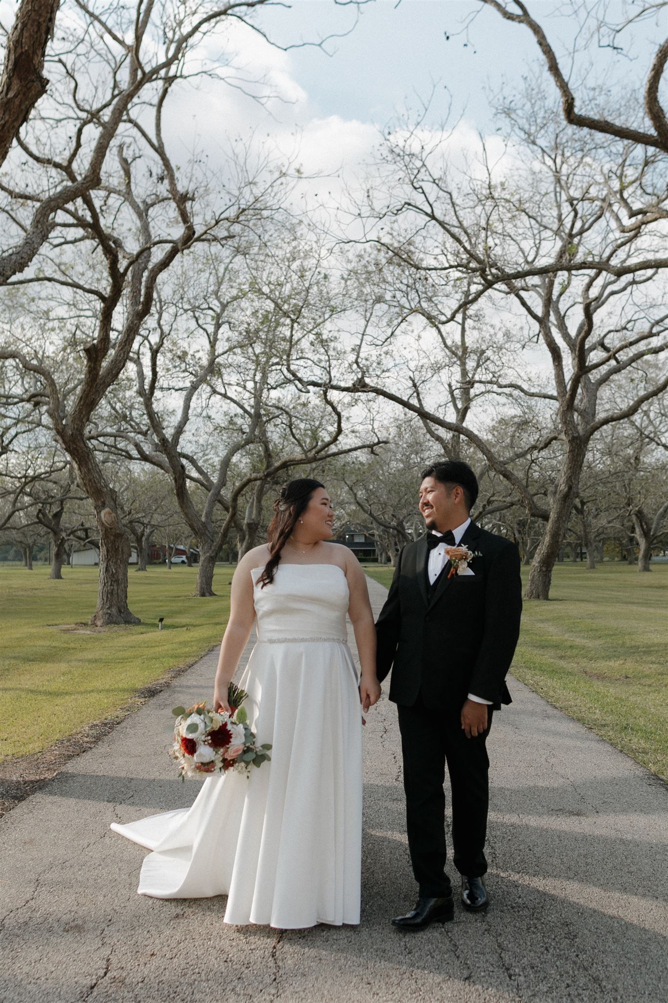 Wedding couple shares a sweet moment on a pathway surrounded by winter trees.
