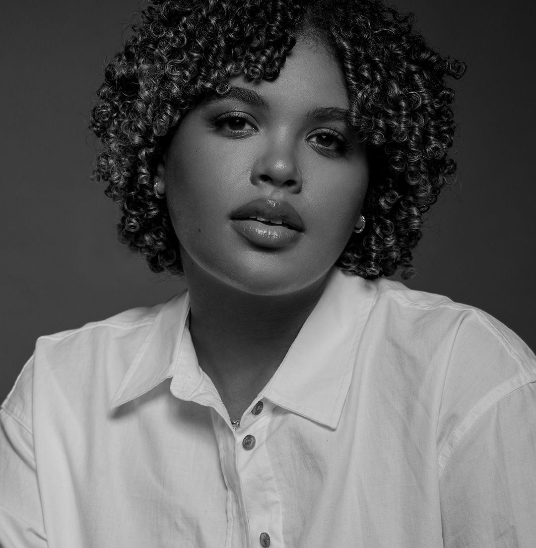 Dramatic black and white portrait with defined curls and white collar shirt.