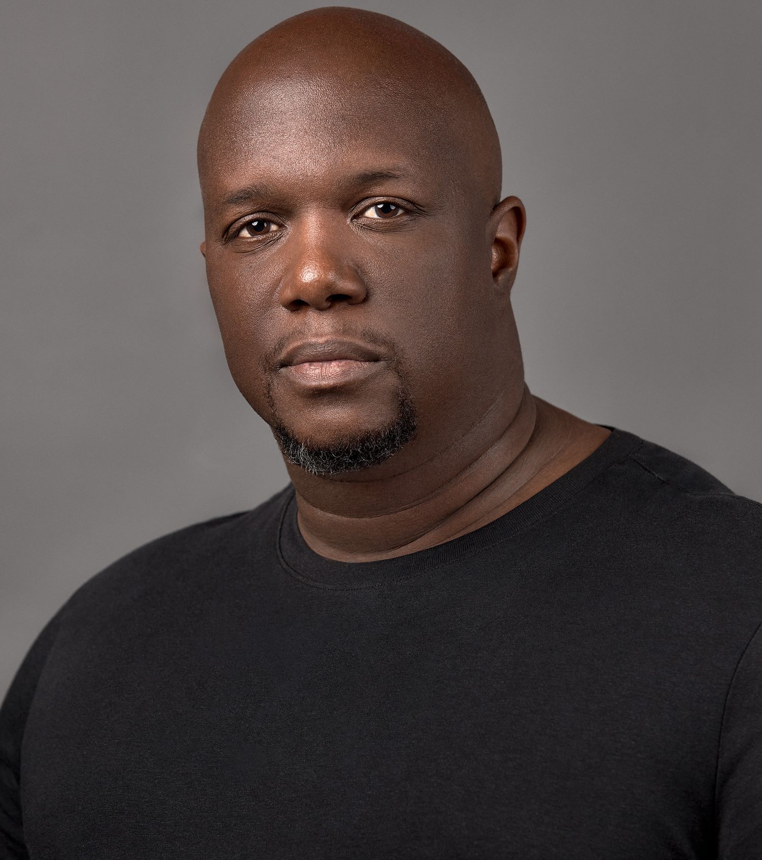 Closeup portrait of person in black shirt against gray background.