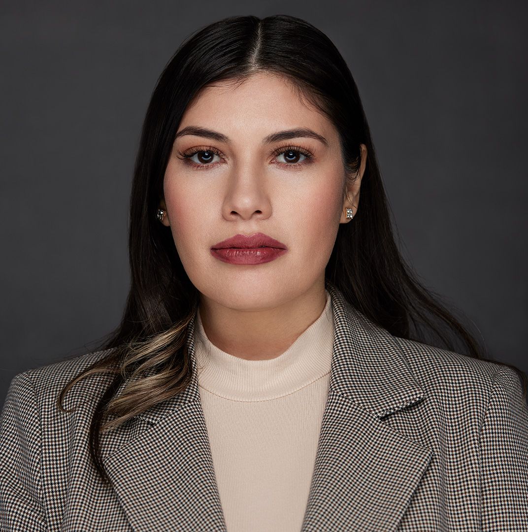 Business portrait in checked blazer and cream turtleneck with sleek styling.