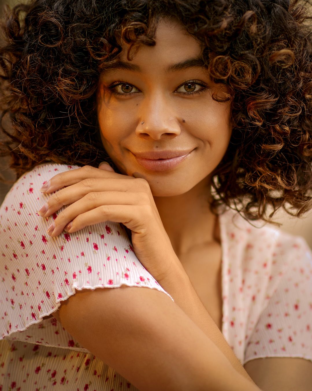 Close-up portrait featuring natural curls and polka dot summer dress in warm lighting.