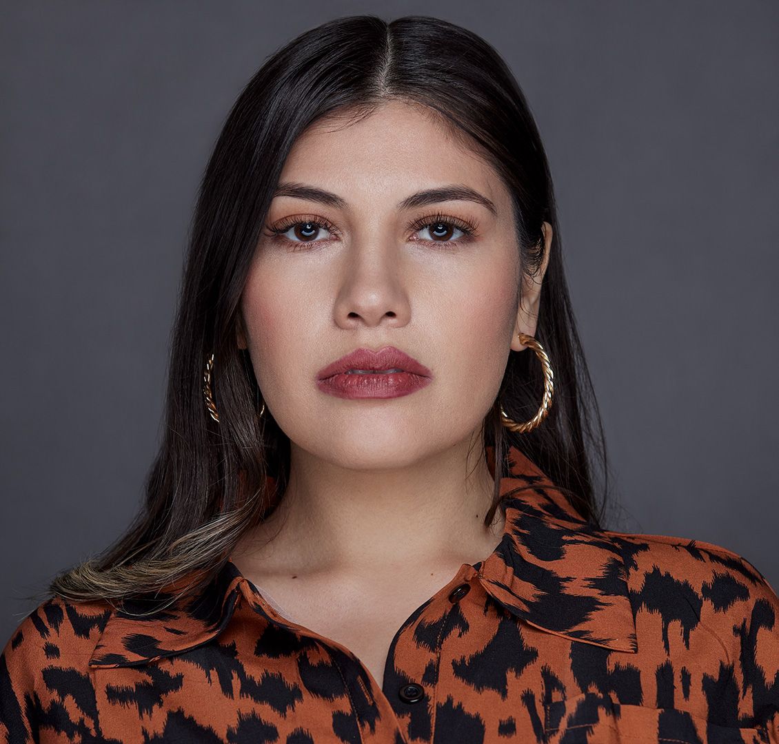 Fashionable portrait in orange and black patterned top with gold hoop earrings.