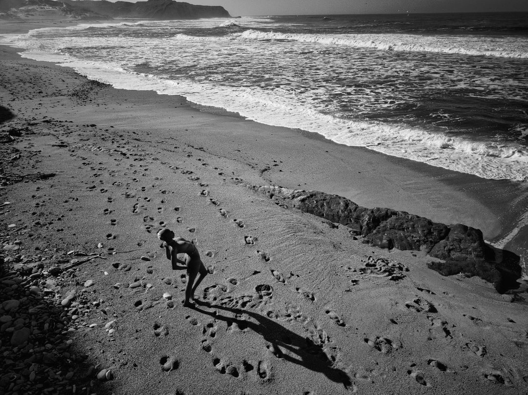 Black and white aerial beach photograph showing shadow cast on sandy shoreline.