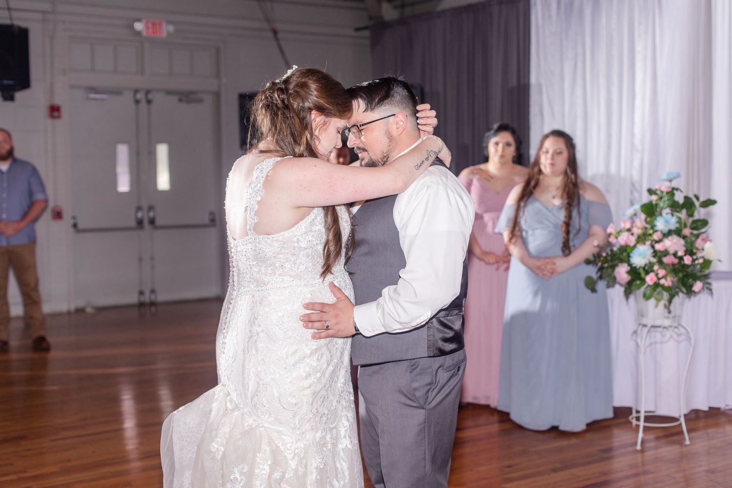 Wedding reception venue with white drapes, hardwood floors and romantic ambient lighting.