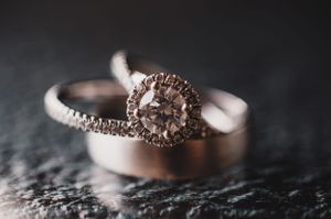 Close-up of an elegant halo diamond engagement ring paired with a rose gold wedding band.