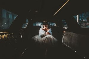 Bride and groom share an intimate kiss inside a dimly lit vintage car on their wedding night.