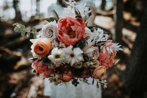 Beautiful bridal bouquet featuring coral peonies, blush roses, white flowers, and eucalyptus greenery.