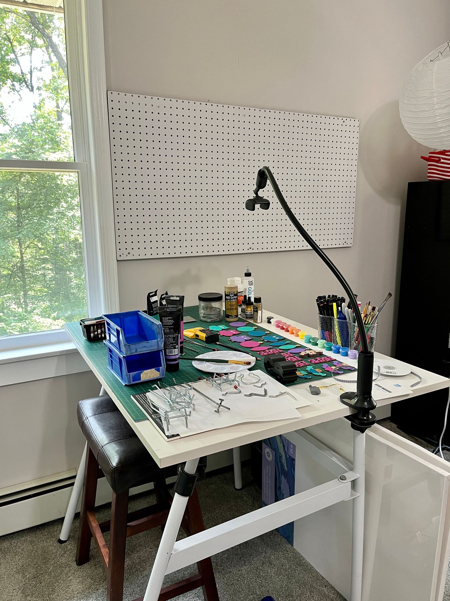 Photo of beginning stage of organizing art studio table and supplies using a pegboard.