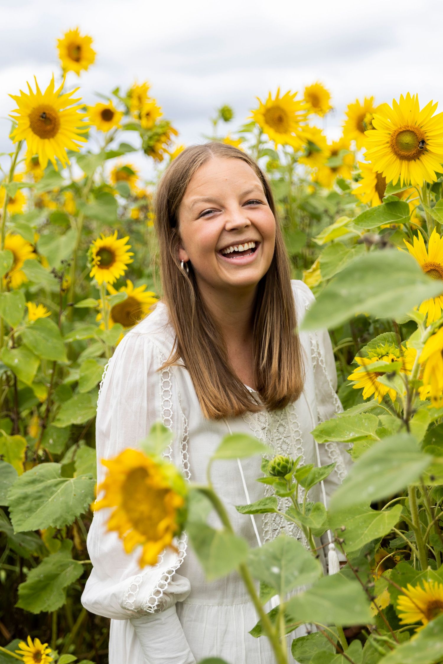 Fotografen bak kamera! Smiler mot kamera midt i en eng av solsikker.