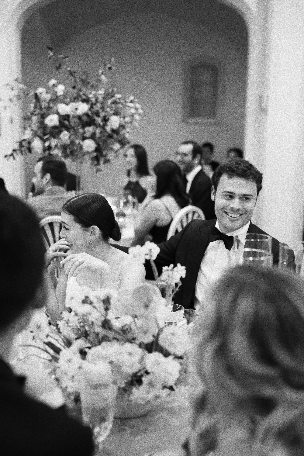 Wedding reception scene with elegant floral centerpieces and formal table settings.
