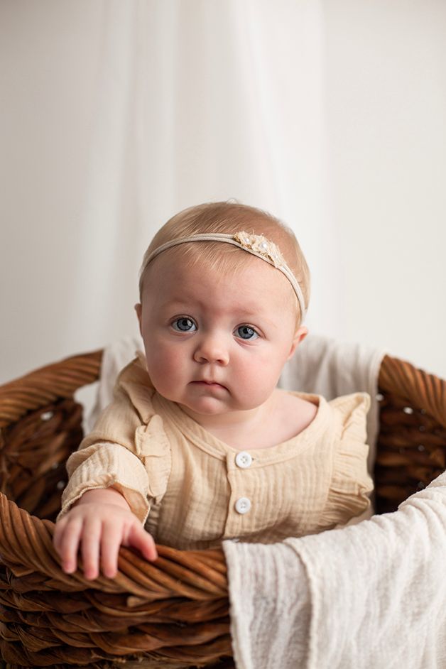Six month old baby girl sitting in woven basket close up of her perfect little face.