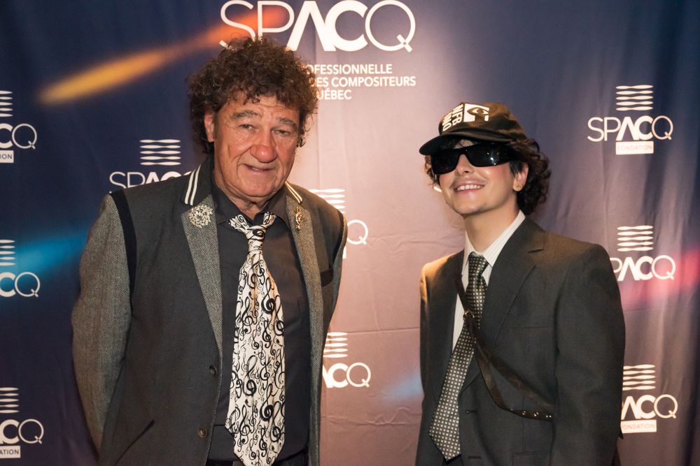 Two people posing in front of a SPACQ event backdrop with branded lighting.